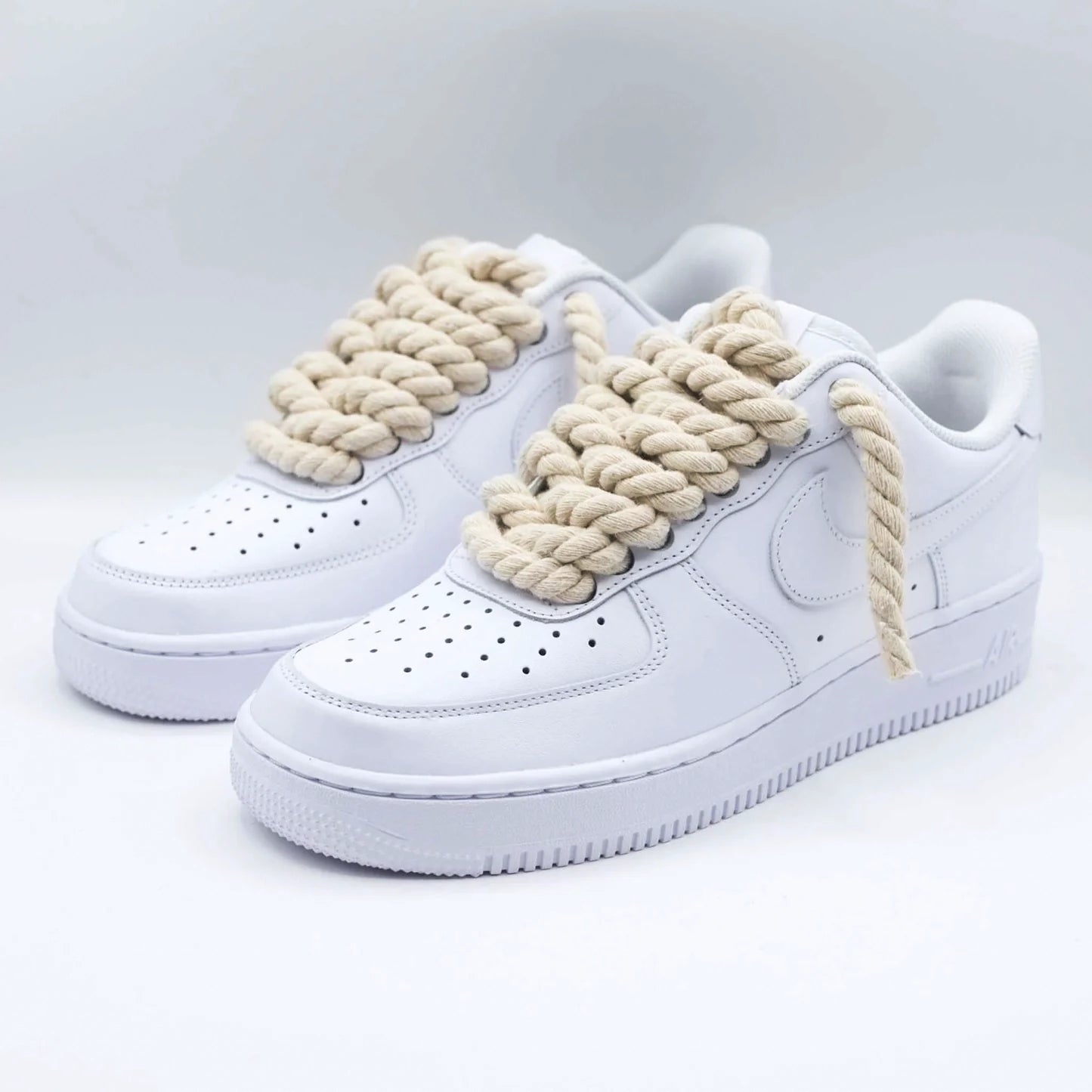 Detail bielych Nike Air Force 1 s béžovými rope laces z predného bočného pohľadu